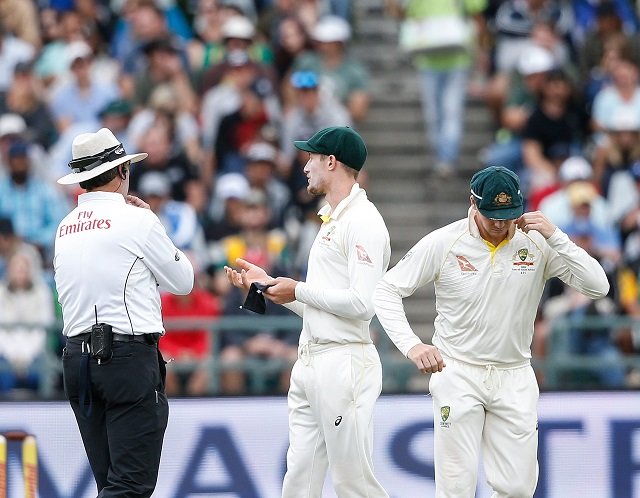 Australian fielder Cameron Bancroft (R) is questioned by Umpires Richard Illingworth (L) and Nigel Llong (not in picture) during the third day of the third Test cricket match between South Africa and Australia at Newlands cricket ground on March 24, 2018 in Cape Town. PHOTO: AFP
