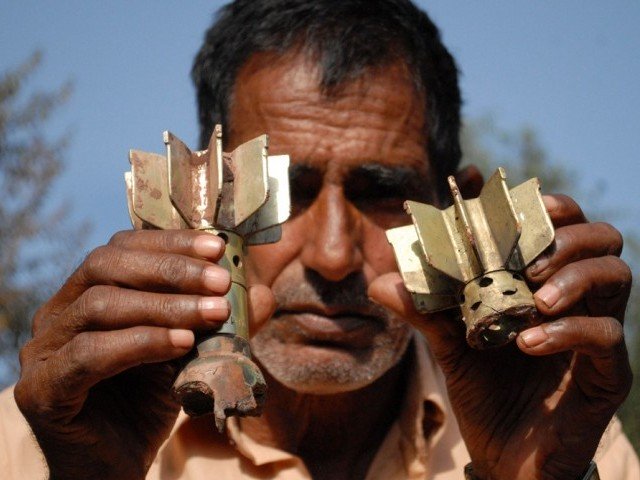 A man displaysmortar shrapnel allegedly fired across the Line of Control (LoC) between Pakistan and India, in the Kotli sector of Azad Kashmir on October 8, 2014. PHOTO: AFP