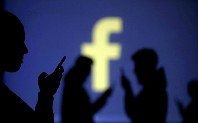 Silhouettes of mobile users are seen next to a screen projection of Facebook logo in this picture illustration taken March 28, 2018.
PHOTO: REUTERS