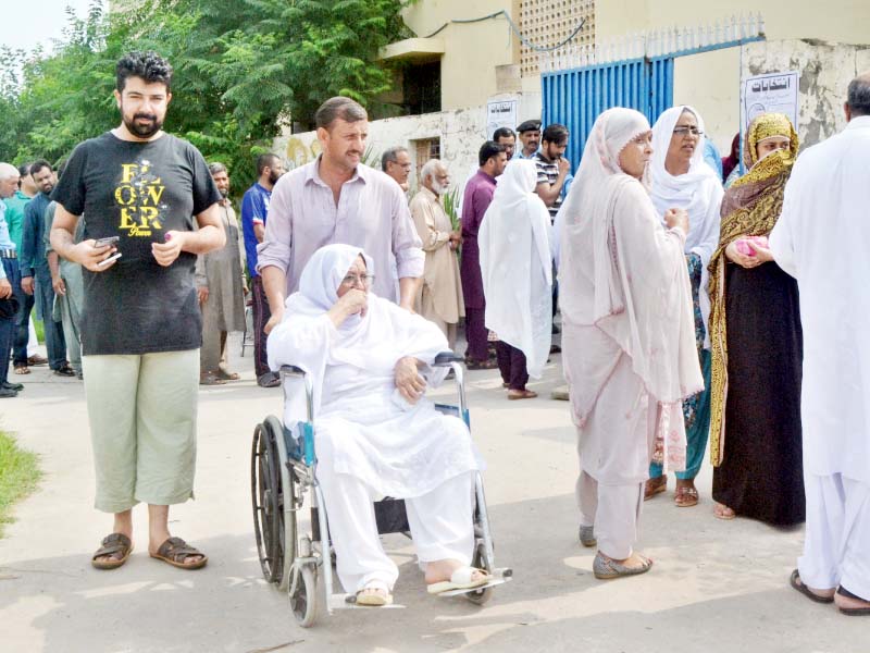 A man wheels his elderly mother out of a polling station in Islamabad. PHOTO: WASEEM NAZIR/EXPRESS