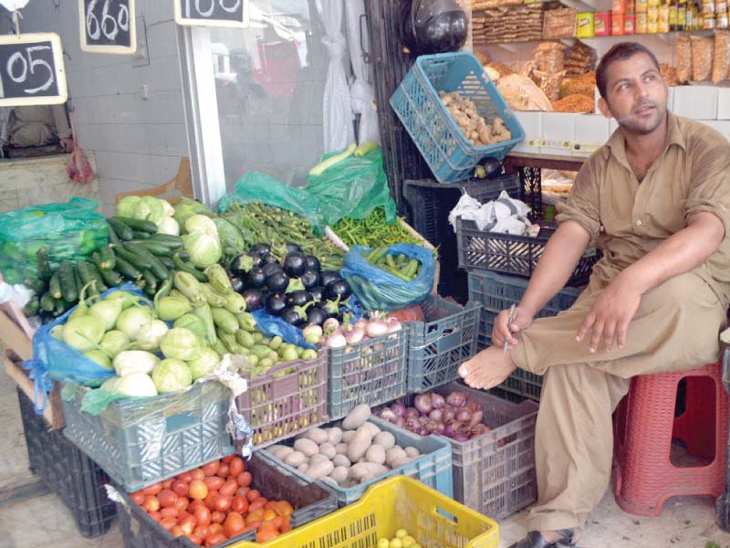 A vegetable vendor sits at his stall. PHOTO: WASEEM NAIZR/EXPRESS