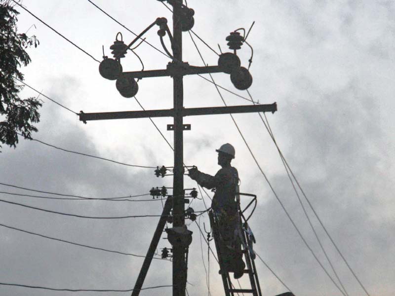 A K-Electric employee repairs electric wires on a pole in North Nazimabad. Many localities in the city plunged into darkness on Tuesday due to the tripping of Extra High Tension wires. PHOTO: ONLINE