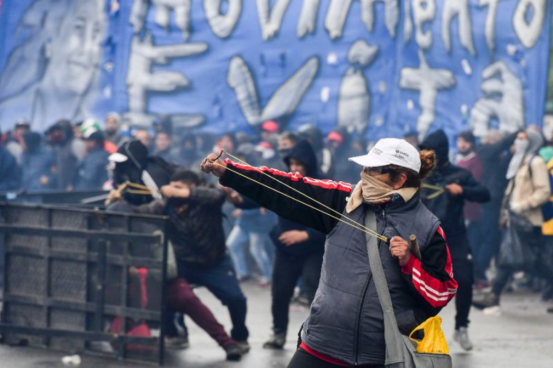 A demonstrator in Argentina fires a slingshot at riot police outside Congress ahead of a vote. PHOTO AFP