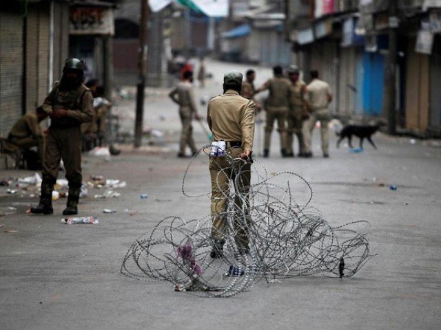 An Indian policeman pulls concertina wire to lay a barricade on a road during a curfew in Srinagar July 12, 2016. PHOTO:REUTERS/FILE