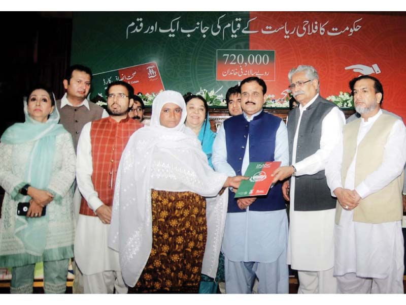 A woman receives a Sehat Card during a ceremony held at the main auditorium of the Faisalabad Medical University on Friday. PHOTO: APP