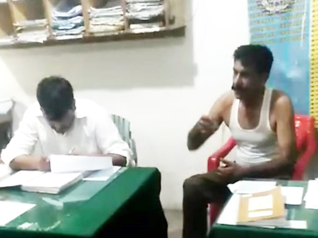 A screengrab of the viral footage of Sub-inspector (right) and the officer (left) in the Rawalpindi police station. PHOTO: EXPRESS