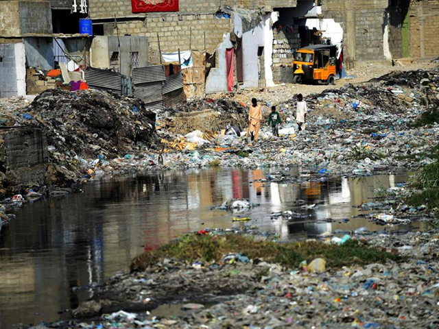 Citizens walk amongst dumped garbage at a residential area of Karachi. PHOTO: AFP