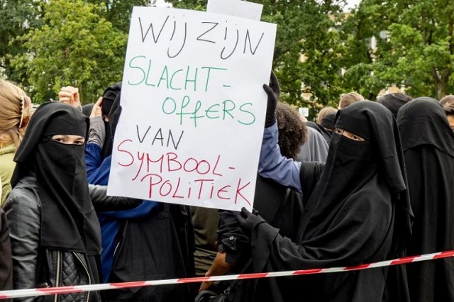 Women wearing niqab, hold a sign reading " We are the victims of symbolism politics" as they demonstrate against the ban of a face-covering veil in the Hague, on Aug 9, 2019. PHOTO: AFP