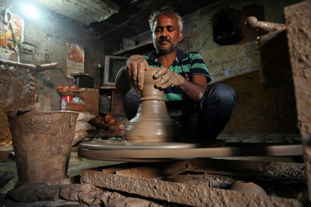A potter makes a clay pot in his residence at Kumhar Gram (Potter's Village) in New Delhi. PHOTO: AFP