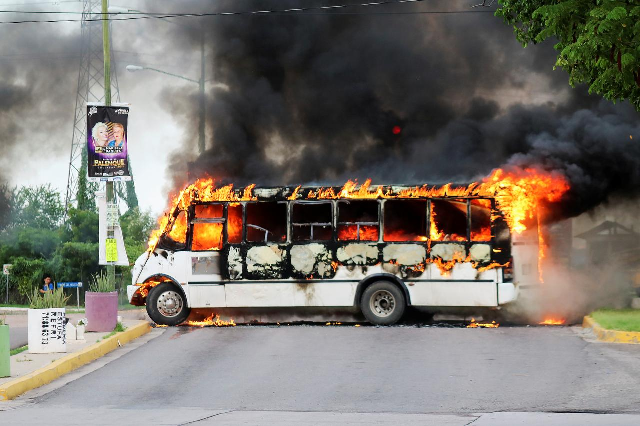 A burning bus, set alight by cartel gunmen to block a road, is pictured during clashes with federal forces following the detention of Ovidio Guzman. PHOTO: Reuters