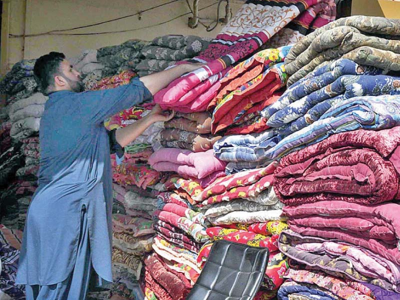 A shopkeeper arranges cotton filled quilts at his shop in Islamabad. PHOTO: APP
