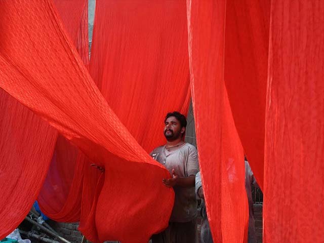 A labourer hangs fabrics to dry after a dyeing process in Lahore. PHOTO: GETTY