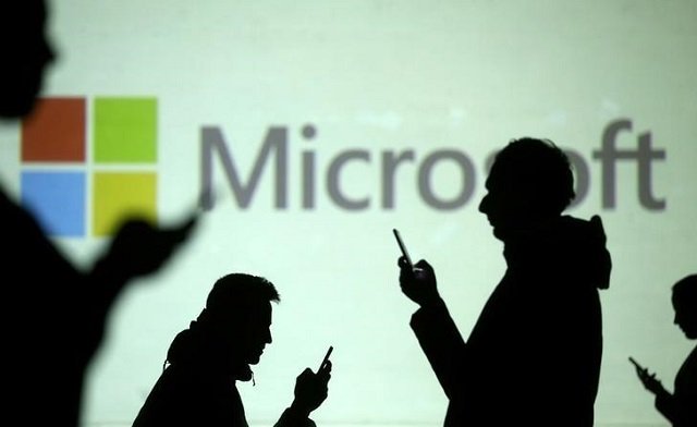 Silhouettes of mobile users are seen next to a screen projection of Microsoft logo in this picture illustration taken March 28, 2018.
PHOTO: REUTERS