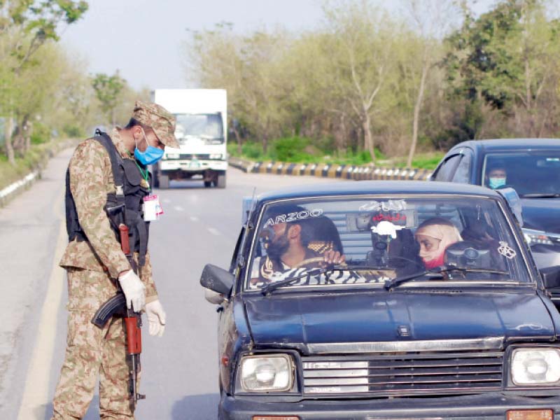 A soldier inquires a family in a vehicle at a check-post during a lockdown in Bhara Kahu. PHOTO: REUTERS