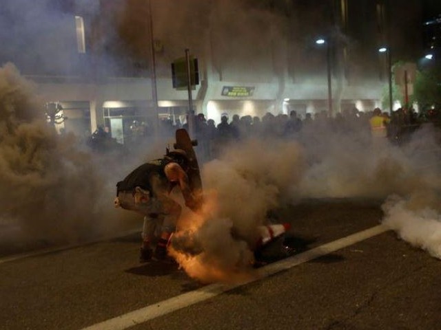 A protester shields himself from tear gas with his skateboard while demonstrating against the death in Minneapolis police custody of African-American man George Floyd, and of Dion Johnson, who was killed in Arizona, outside of Phoenix police headquarters in Phoenix, Arizona, US. PHOTO: REUTERS
