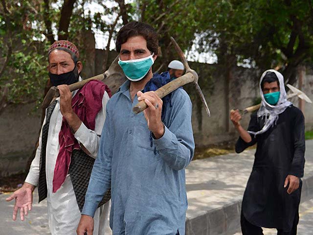 Pakistani labourers walks along a street during a government-imposed lockdown. PHOTO: AFP