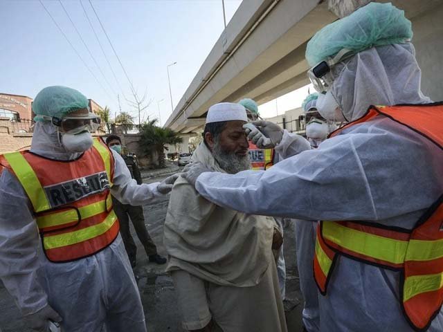 Pakistani rescue personnels check the body temperature of a man during a drill. PHOTO: AFP