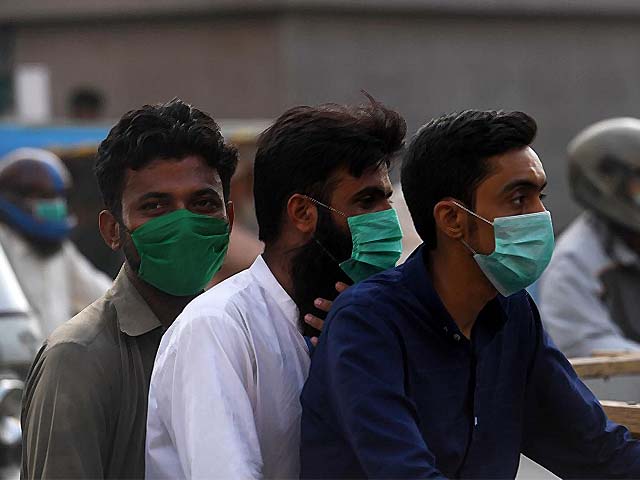 Commuters wearing face-masks ride on a bike. PHOTO: AFP