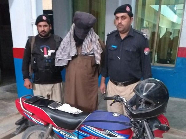 Police pose with the man arrested for the murder of Ahmaddiya community professor in Peshawar. PHOTO: EXPRESS