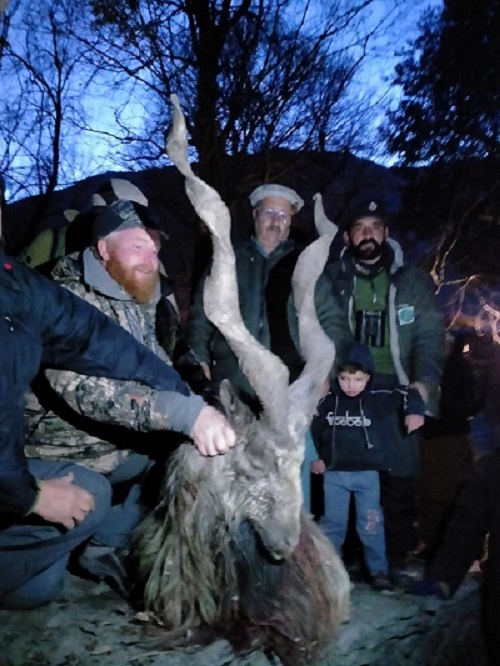 People gather around as American hunter Edward Joseph Hudson poses with the longest horned Markhor he hunted down in Chitral. PHOTO: EXPRESS