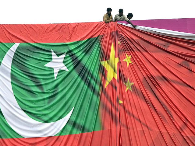 Workers set up a billboard welcoming President Xi Jinping to Pakistan ahead of his visit in 2015. PHOTO: AFP